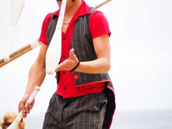 Midsection of man juggling against clear sky