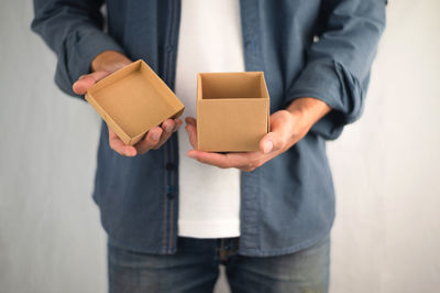 Midsection of man holding paper while standing against wall