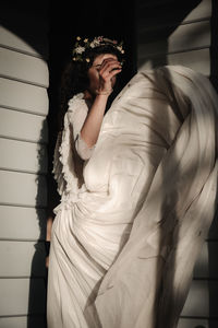 Young woman wearing dress standing against wall