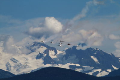 Airplane flying over snowcapped mountains against sky