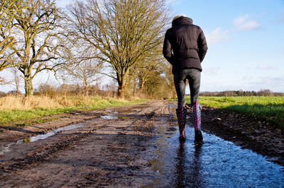 Rear view of woman walking on dirt road