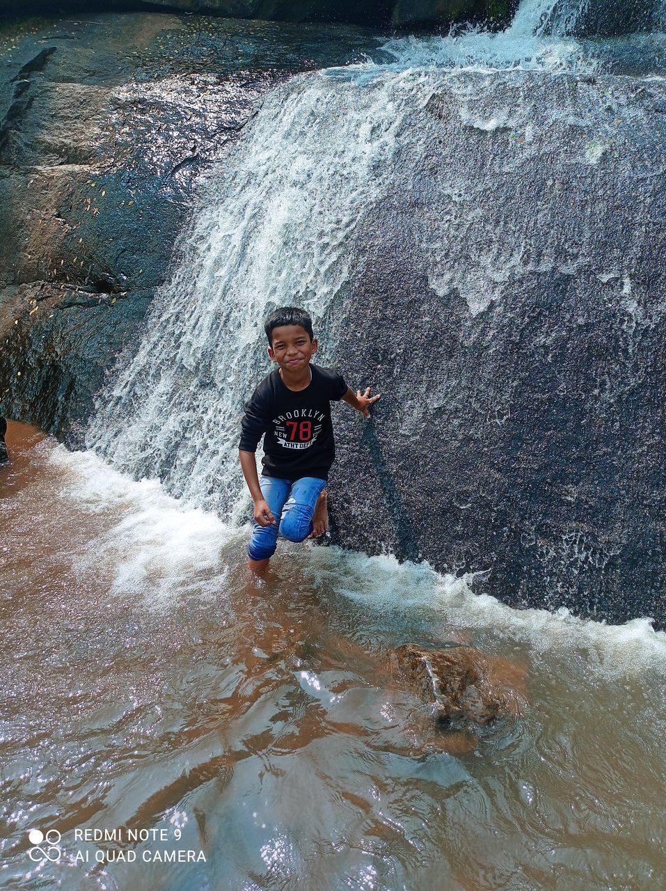 water, one person, leisure activity, lifestyles, motion, nature, sports, men, front view, day, full length, beauty in nature, young adult, adventure, extreme sports, outdoors, sea, splashing, water sports, high angle view, waterfront, adult, holiday, rapid, scenics - nature, vacation, rock, trip, enjoyment, portrait, land, casual clothing, surfing, waterfall, looking at camera, wave