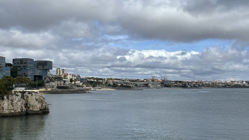 Buildings by sea against sky