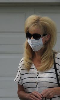 Mature woman wearing mask standing against door