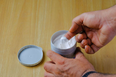 Cropped hand of woman holding bottle on table