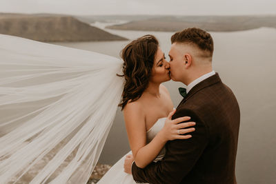 Side view of couple standing at beach