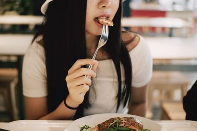 Midsection of woman eating food at table
