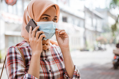 Portrait of young man holding smart phone on street