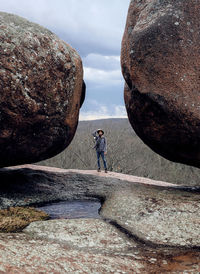 Full length of man standing amidst boulders against sky