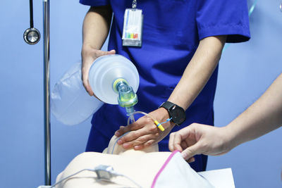 Midsection of doctor practicing on cpr dummy at hospital