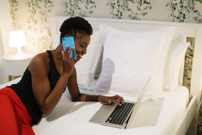 Man using mobile phone while sitting on bed