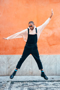 Full length of man with arms raised against wall