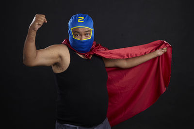 Portrait of man in costume flexing muscles against black background