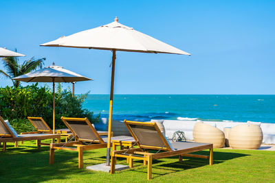 Deck chairs and tables on beach against sky