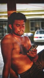 Shirtless man using phone