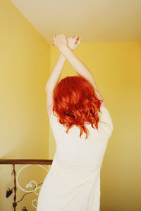 Rear view of woman standing against white wall