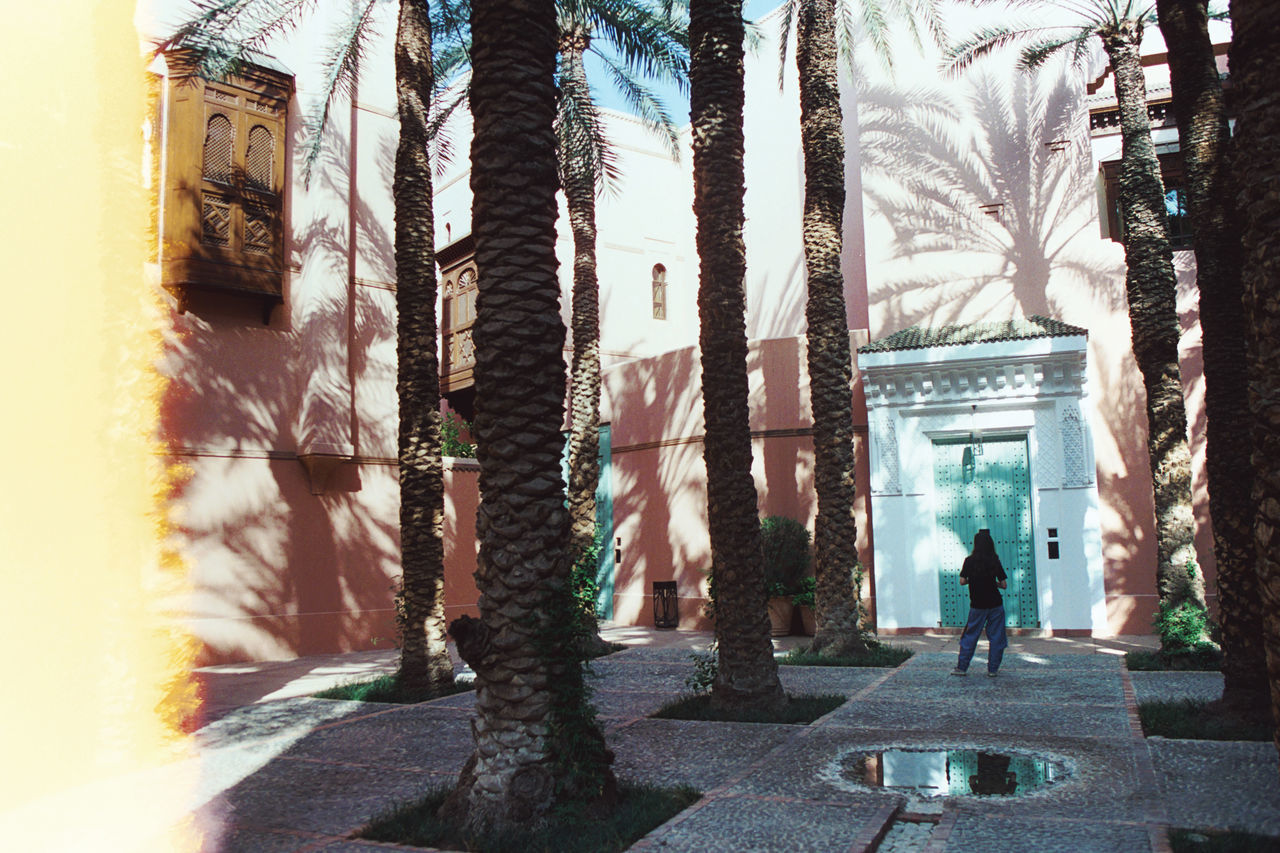 REAR VIEW OF MAN STANDING AGAINST BUILDING