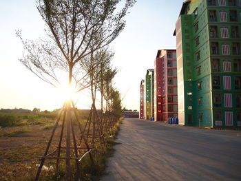 Road amidst buildings against sky during sunset
