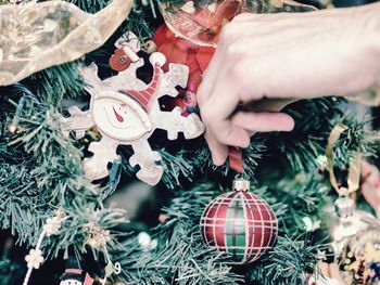 Cropped hand of person decorating christmas tree