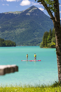 Rear view of people relaxing in lake