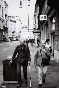 Rear view of people walking on street in city