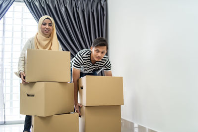Couple holding cardboard boxes while standing at new home