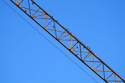 Low angle view of crane against clear blue sky