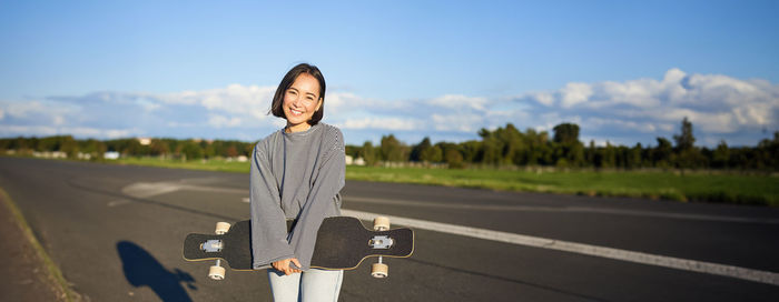 Portrait of young woman standing against sky