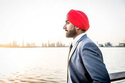 Businessman wearing turban looking away while standing by river