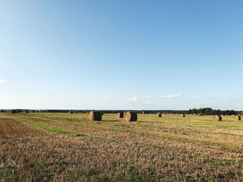 Hay bales on field against clear sky