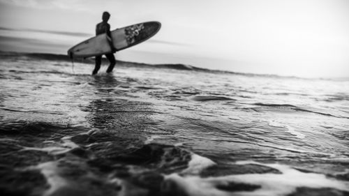 Man surfing on beach against sky