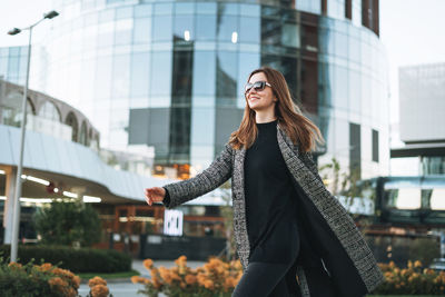 Portrait of young woman standing against building