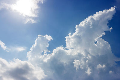 Low angle view of sunlight streaming through clouds