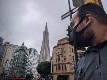 Low angle view of man wearing mask in city