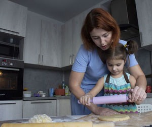 Side view of mother and girl playing with food at home