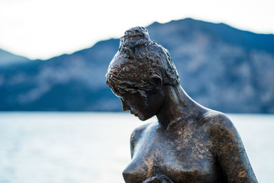 Close-up of statue against sea and mountain
