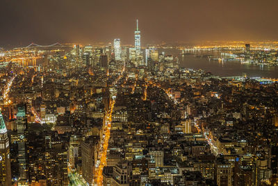 Illuminated modern buildings in city against sky at night