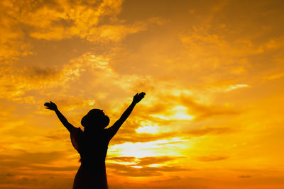 Silhouette woman standing against dramatic sky during sunset