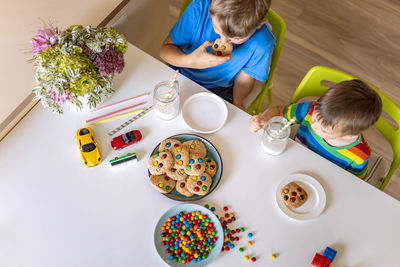 High angle view of brothers eating candies and cookies