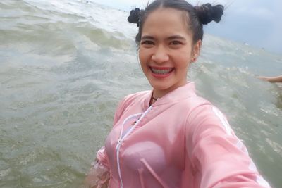 Portrait of smiling young woman standing in sea