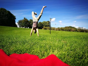 Man jumping on field against sky