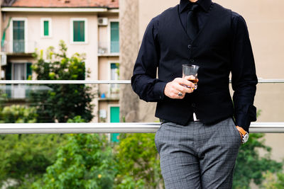 Full length of man holding drink standing against building