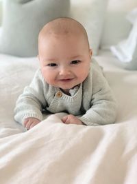 Portrait of cute baby boy lying on bed at home