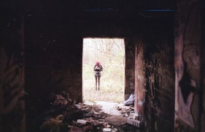 Rear view of woman standing in abandoned building