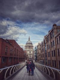 Tourists in front of building against cloudy sky