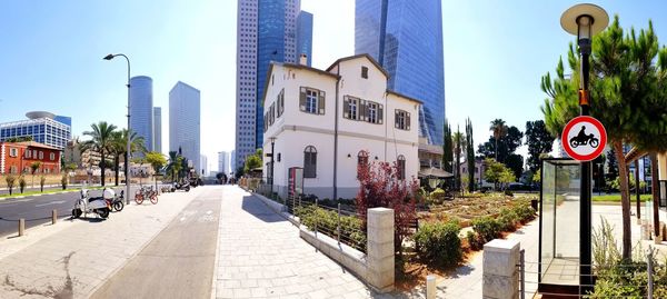 Road amidst buildings in city against sky