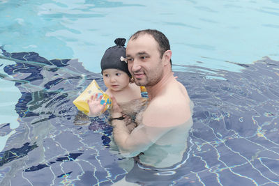 Happy cute asian little girl and her dad spend time together in open air thermal pool.