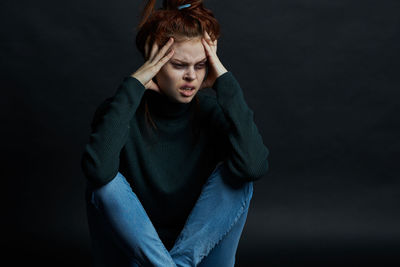 Portrait of beautiful young woman against black background