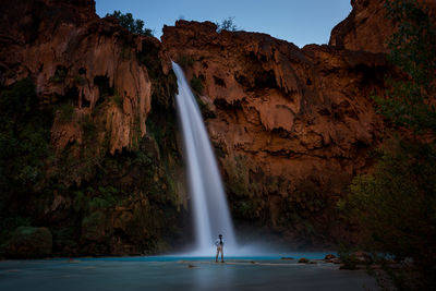 View of man standing in front of waterfall