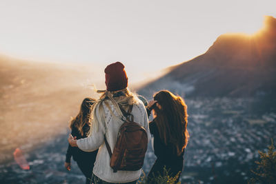 Rear view of couple standing against sky during sunset